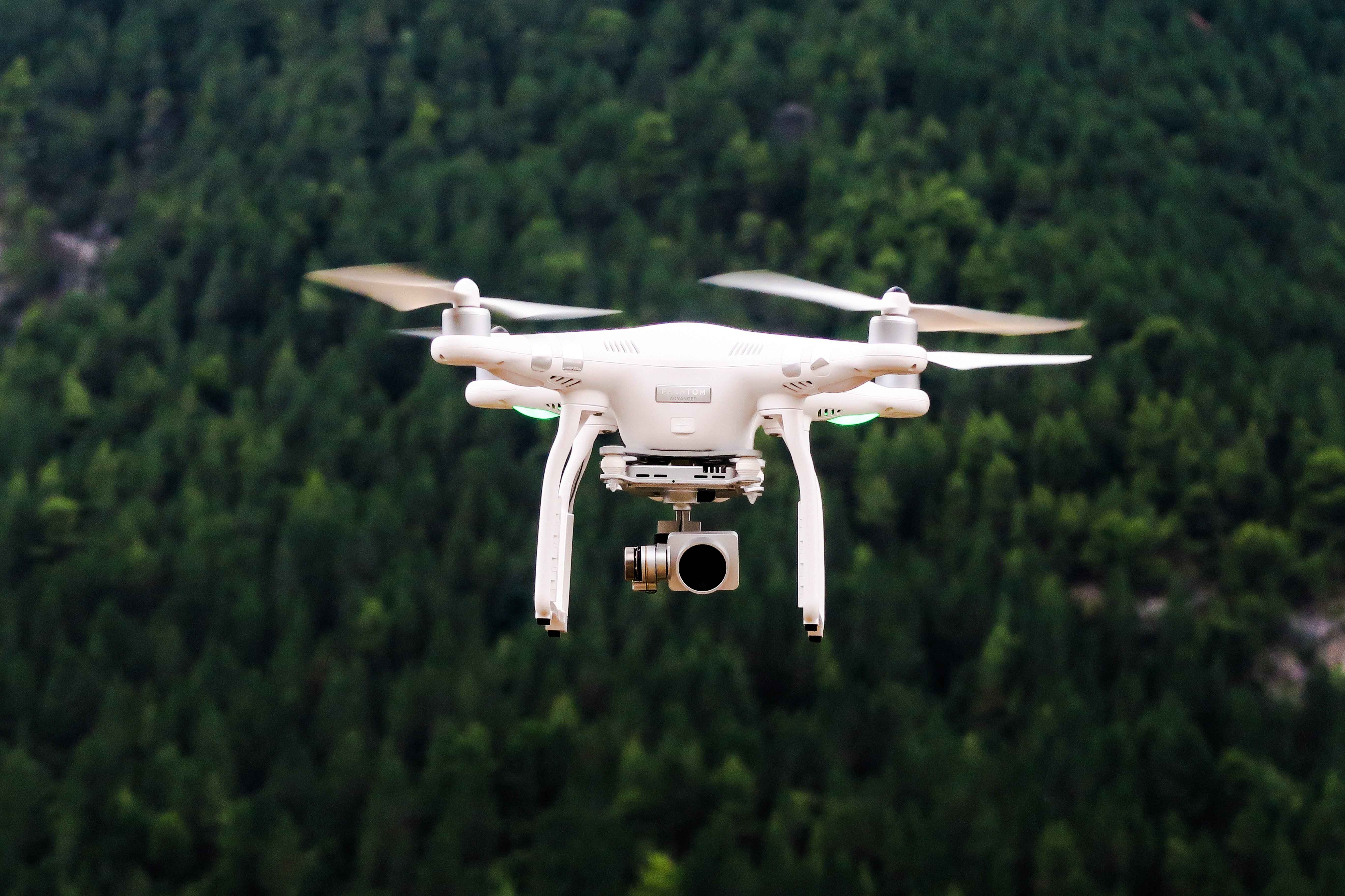 drone flying in mid-air with a forest in the background